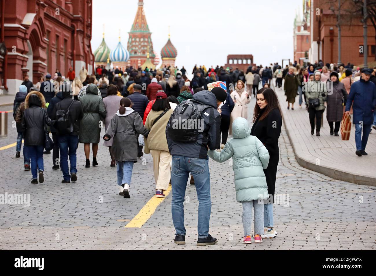 Menschenmenge, die auf dem Roten Platz in Moskau vor dem Hintergrund der Basilius-Kathedrale spazieren gehen, Touristen in der Frühlingsstadt Stockfoto