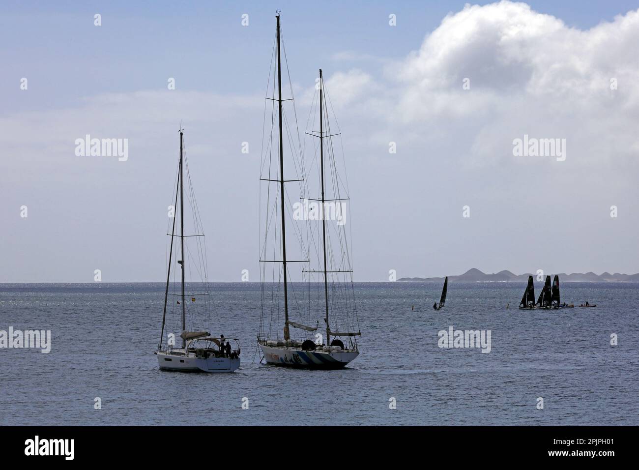 Segelboote an Anlegestellen und Segeltrupps mit schwarzen Segelübungen in der Ferne (deutsche und italienische Boote). Lanzarote, Februar/März 2023. Stockfoto