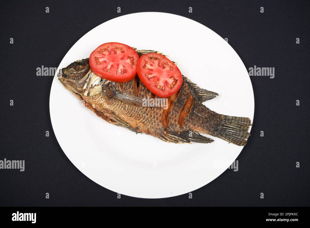Gegrillter Fisch serviert mit Ugali und Gemüse auf abgelegenem Hintergrund Stockfoto