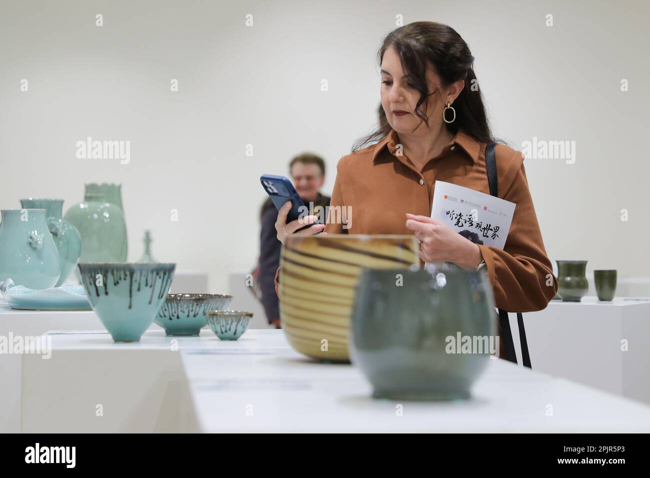 Brüssel, Belgien. 3. April 2023. Ein Besucher fotografiert eine Ausstellung während der Ausstellung „Longquan City Celadon Art“ im Chinesischen Kulturzentrum in Brüssel, Belgien, am 3. April 2023. Die Eröffnungszeremonie der Ausstellung „Longquan City Celadon Art“ fand am Montag im Chinese Cultural Center statt, wo 55 Werke chinesischer Künstler ausgestellt wurden. Kredit: Zheng Huansong/Xinhua/Alamy Live News Stockfoto