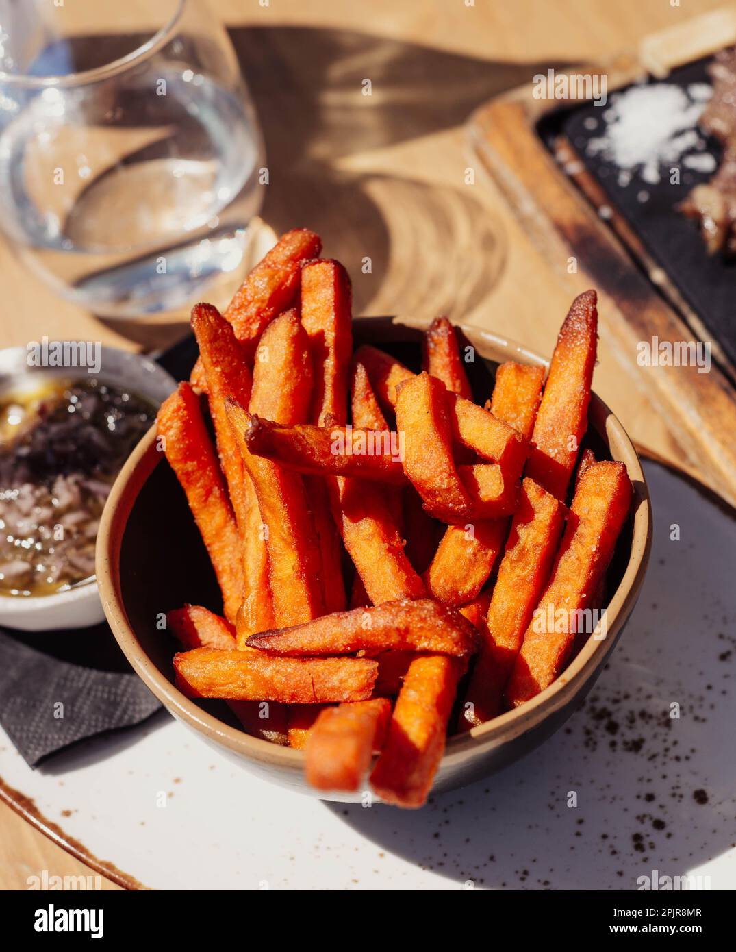 Pommes frites, serviert in einer Schüssel auf einem Holztisch. Süßkartoffeln Stockfoto