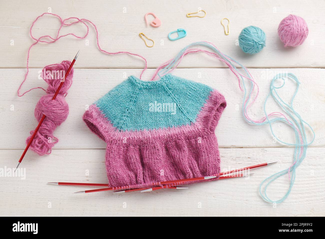 Das Stricken eines Puppenkleids auf Stricknadeln, Strickzubehör Stockfoto