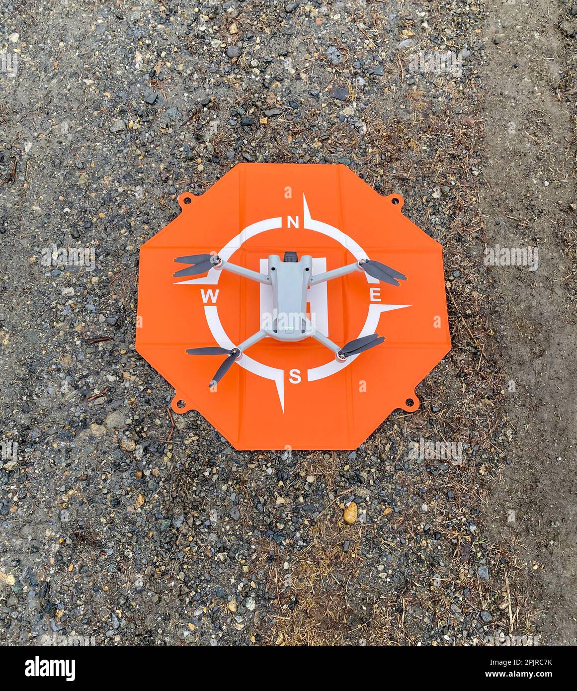 Ich schaue auf eine Drohne auf einem orangefarbenen Startfeld, bereit für den Flug. Stockfoto
