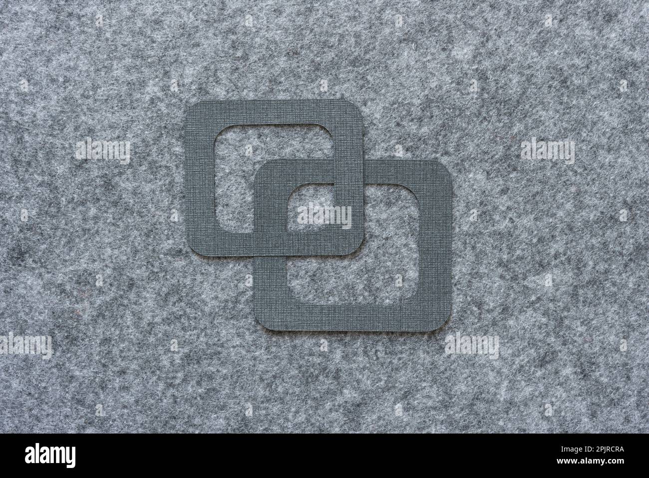 Zwei geschnittene Papierformen (Quadrate mit abgerundeten Ecken) oder Rahmen auf grauem Filzstoff-Hintergrund Stockfoto