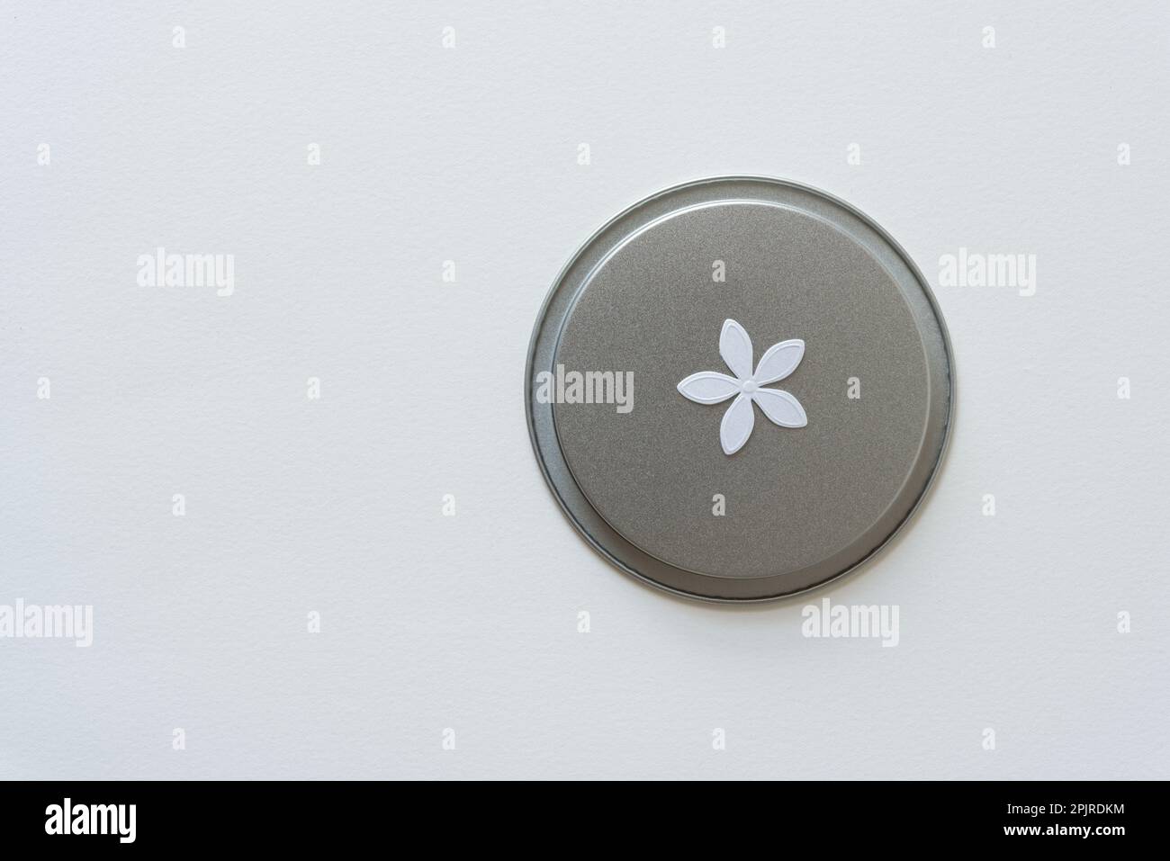 Metalldeckel mit Papierkonfetti-Blume isoliert auf leerem Papier Stockfoto
