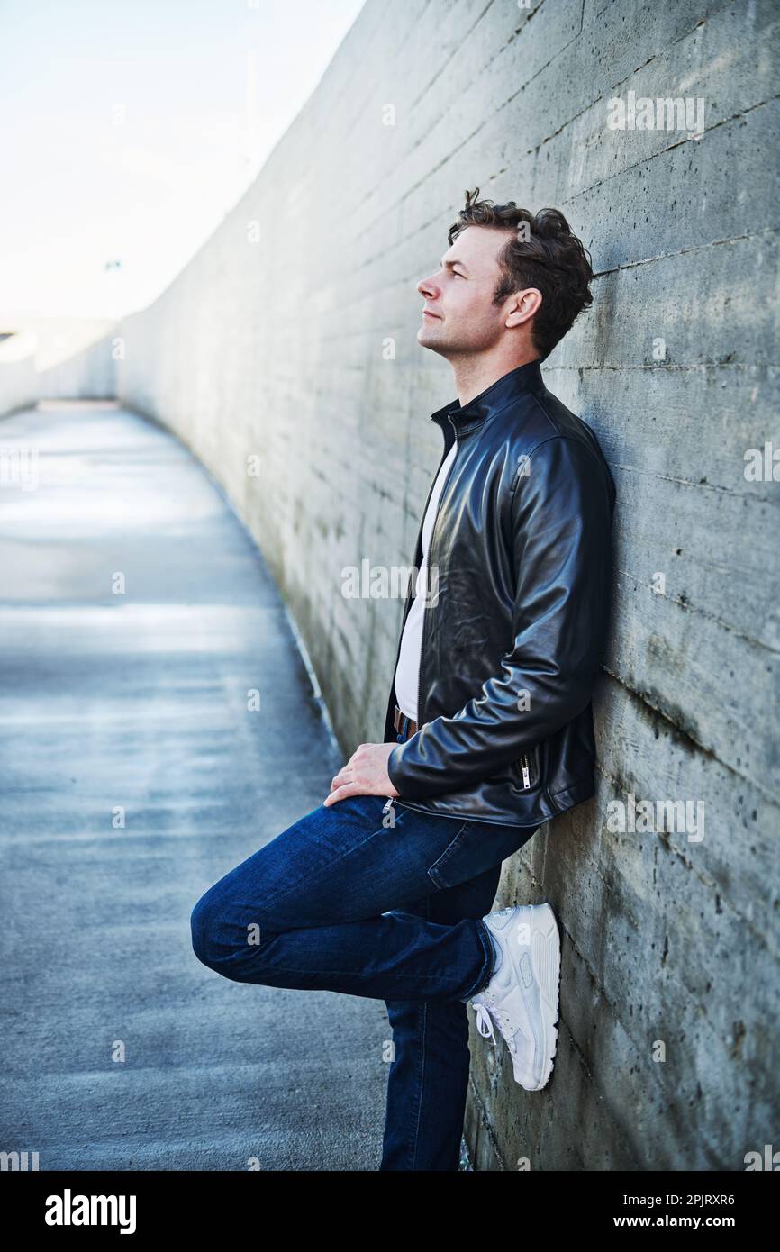 Porträt eines Mannes in Jeans und Lederjacke in urbaner Umgebung Stockfoto