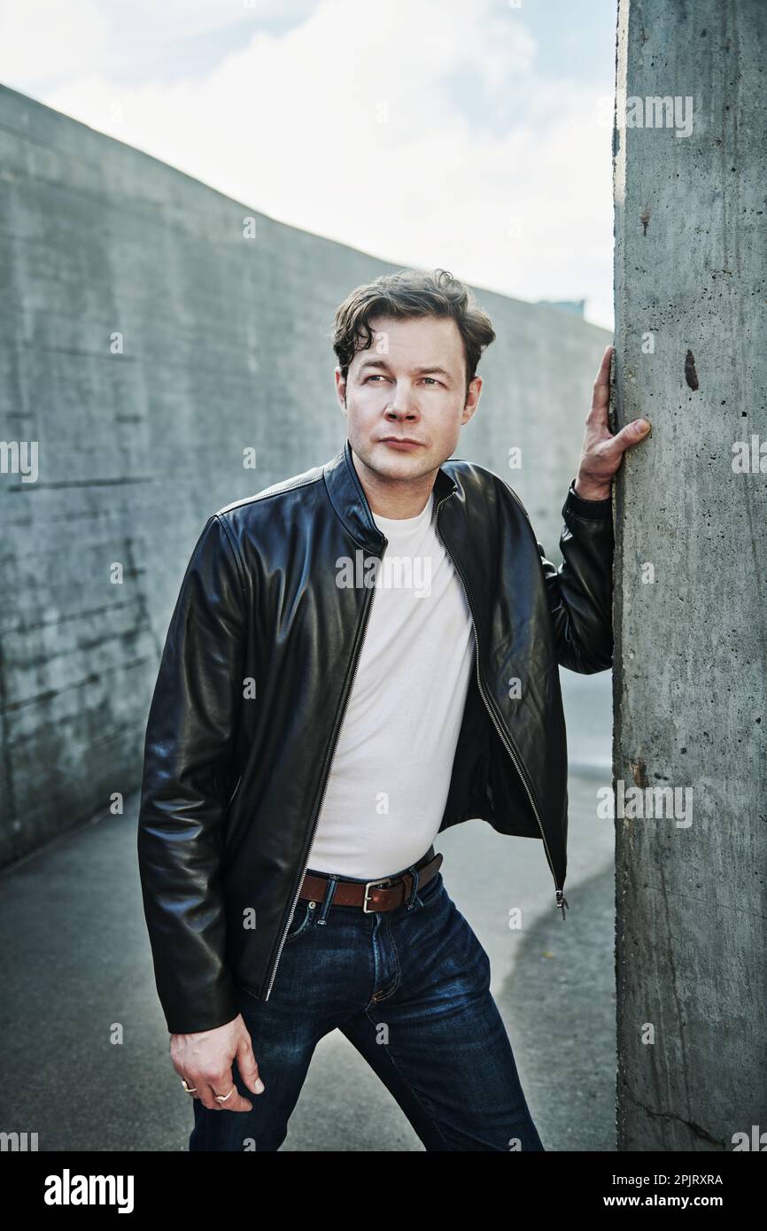 Porträt eines Mannes in Jeans und Lederjacke in urbaner Umgebung Stockfoto