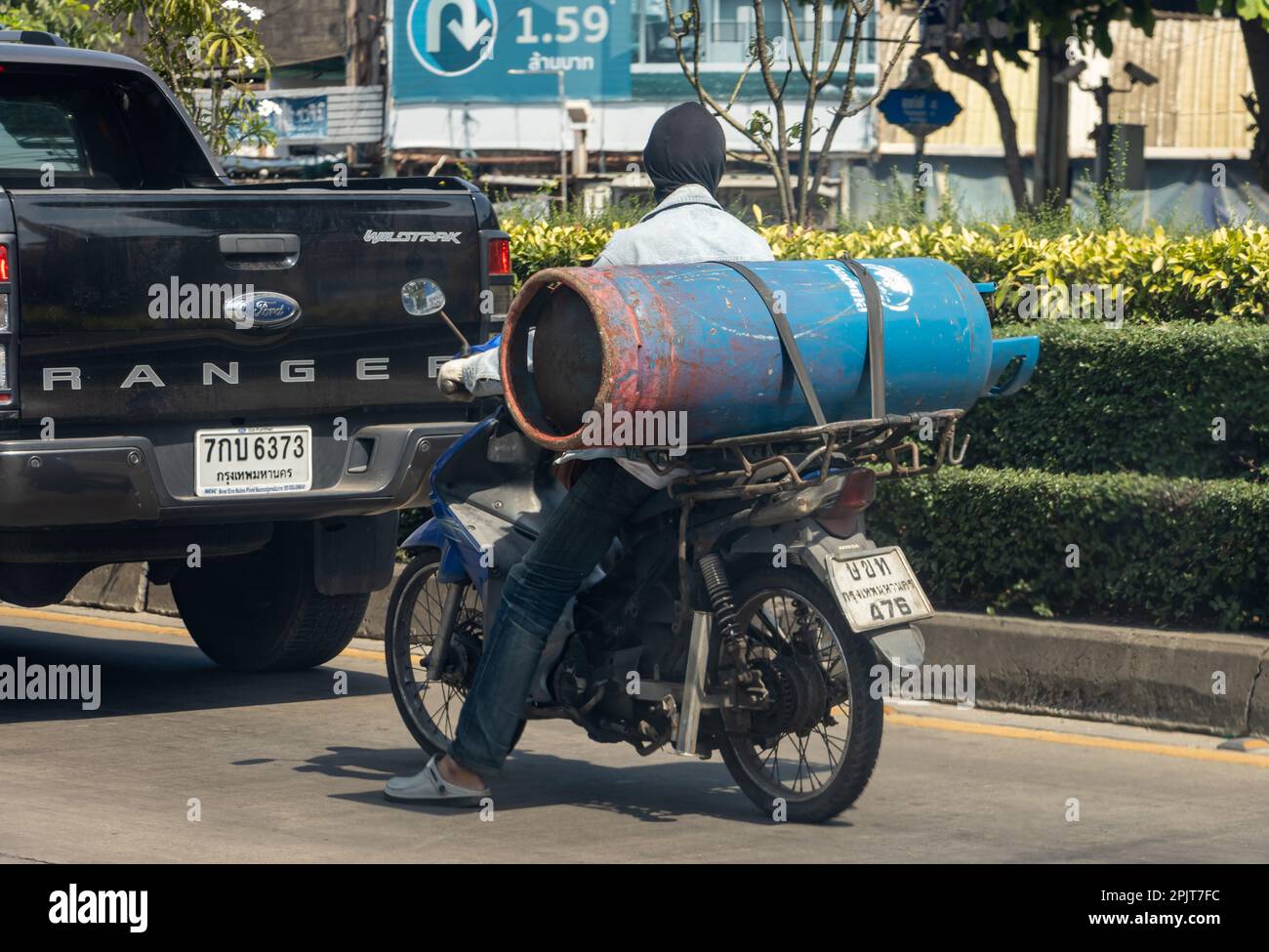 SAMUT PRAKAN, THAILAND, JANUAR 21 2023, Ein Mann transportiert eine große Gasflasche auf einem Motorrad Stockfoto