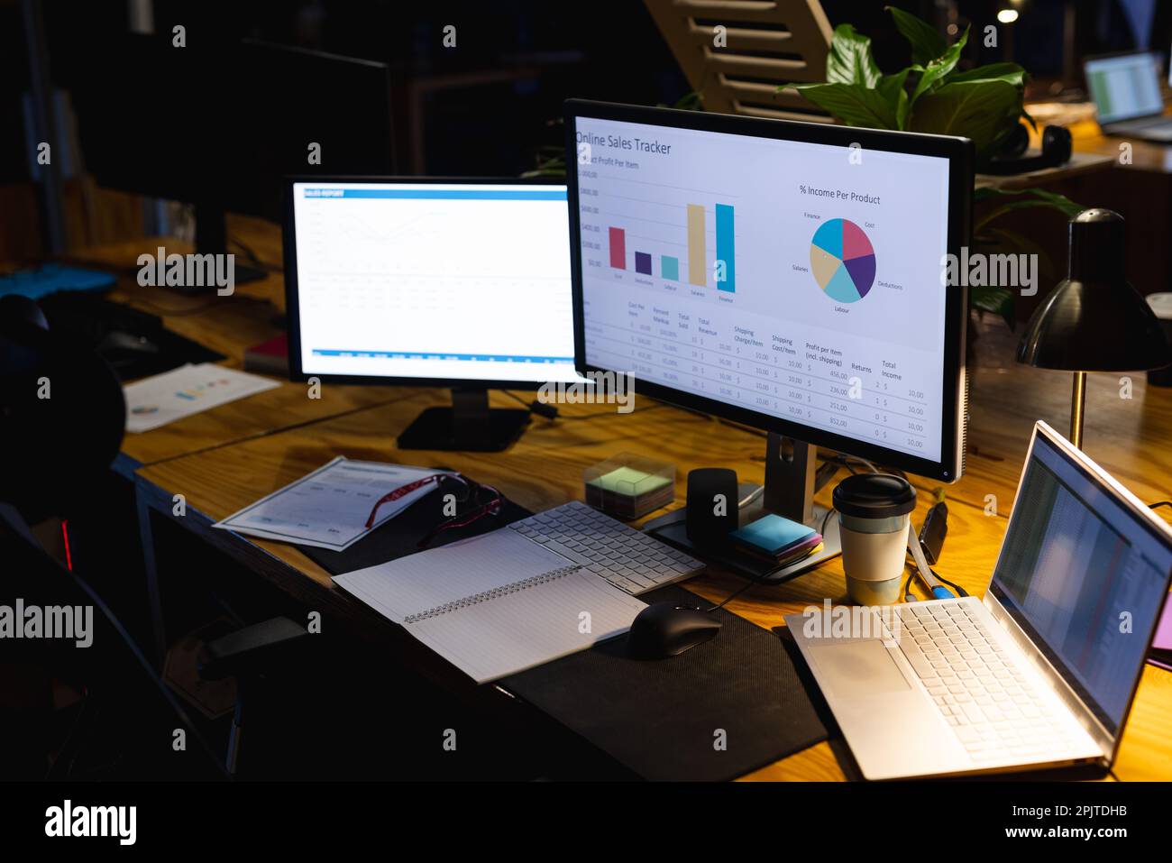 Nahaufnahme des Schreibtischs mit Laptop, Computern, Dokumenten und Notizbuch, die bis spät in die Nacht im Büro arbeiten Stockfoto