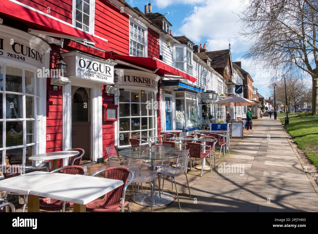 Geschäfte und Cafés auf dem breiten Bürgersteig in der Tenterden High Street, Kent, Großbritannien Stockfoto