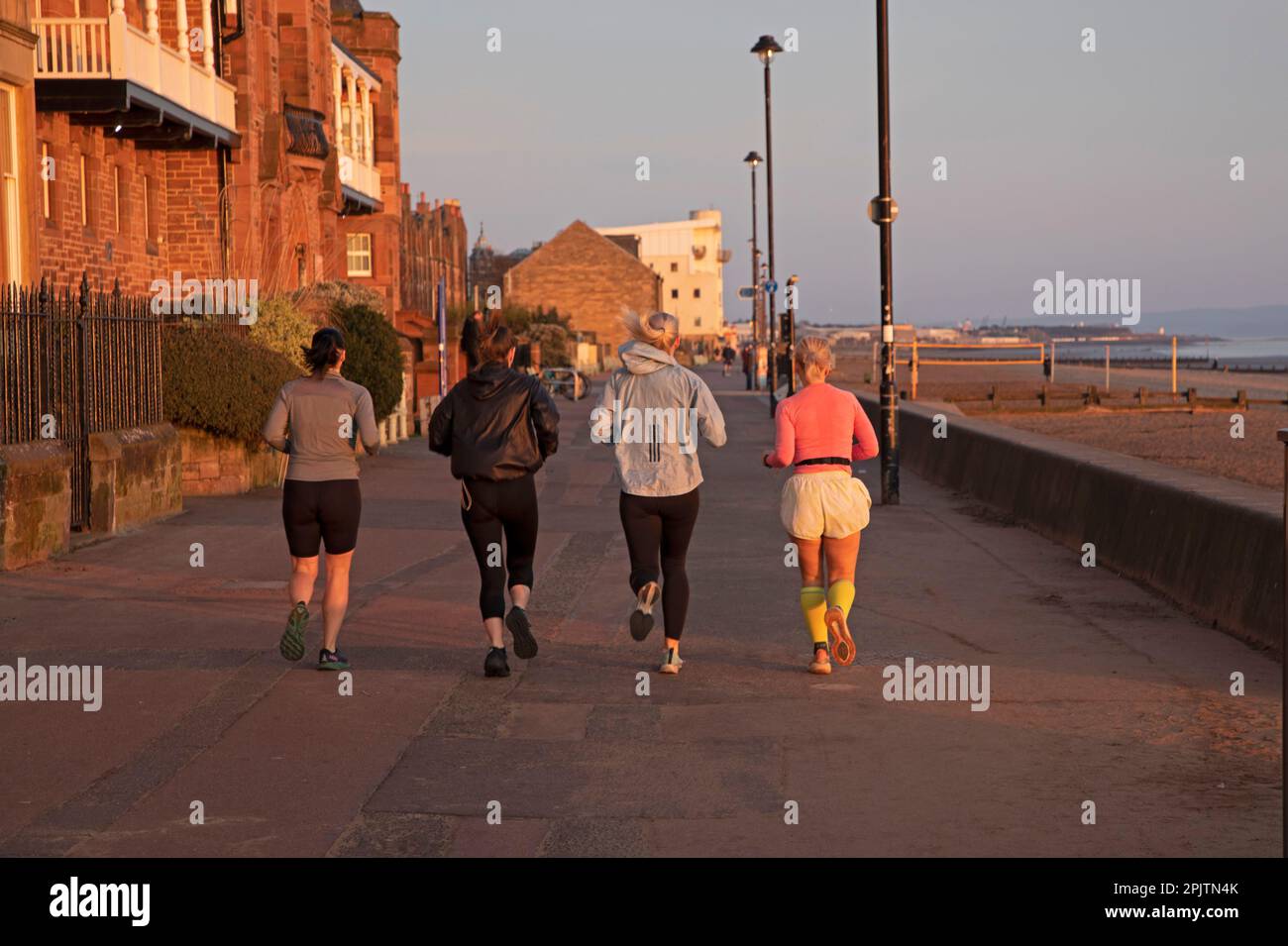 Portobello, Edinburgh, Schottland, Großbritannien. 4. April 2023 Eine Gruppe Joggingweibchen hat eine Feder in ihrem Schritt auf der Promenade bei Sonnenaufgang am Firth of Forth. Kredit: Archwhite/alamy Live News. Stockfoto