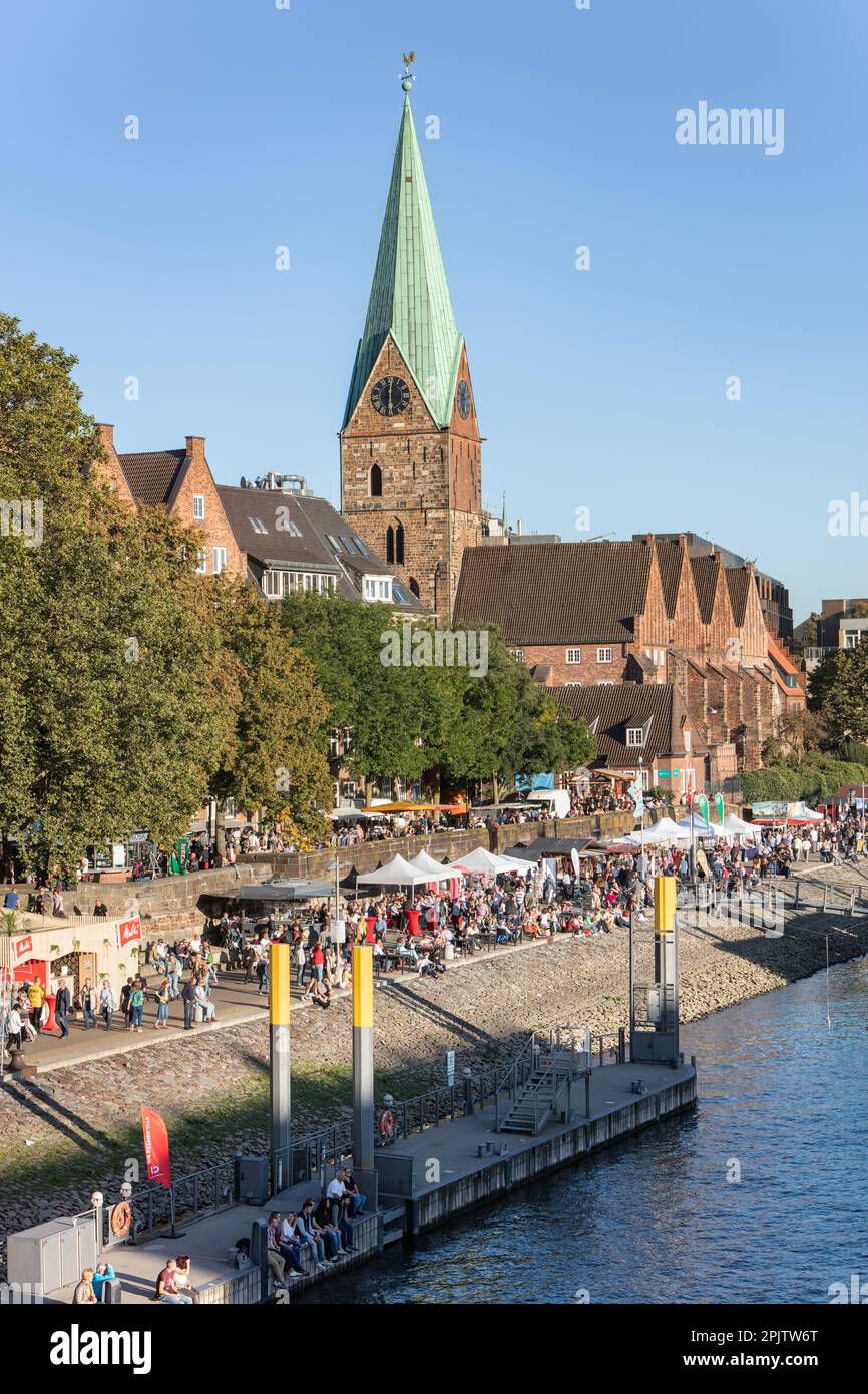 Die Menschen feiern den Martime Day - Maritime Woche in Cafés und Bars an der historischen Schlachte Uferpromenade an der Weser bei der St. Martin's Church. Bremen. Stockfoto