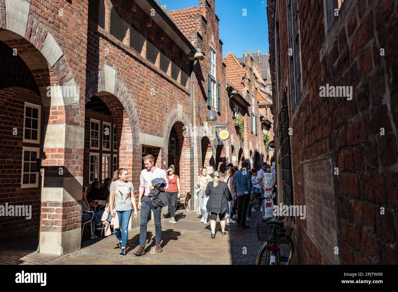 Die Menschen spazieren durch die historische Bottcherstraße aus dem 14. Jahrhundert, wobei viele Gebäude im expressionistischen Stil aus der Bremer Altstadt von 1930er errichtet wurden Stockfoto