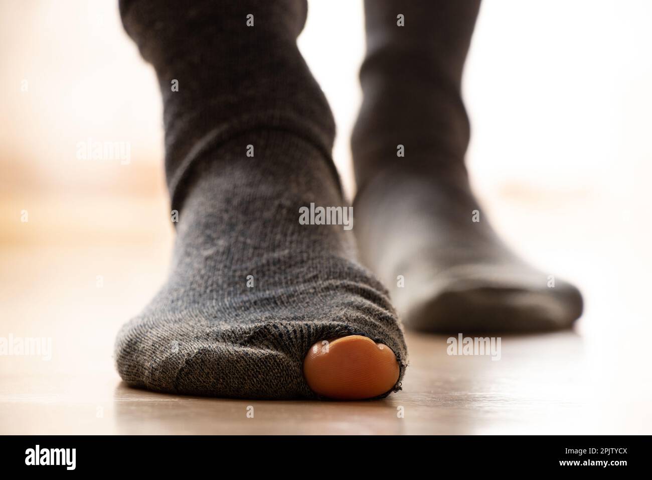 Frauenfüße in heiligen Socken stehen auf dem Boden des Hauses, Armut, Füße Stockfoto