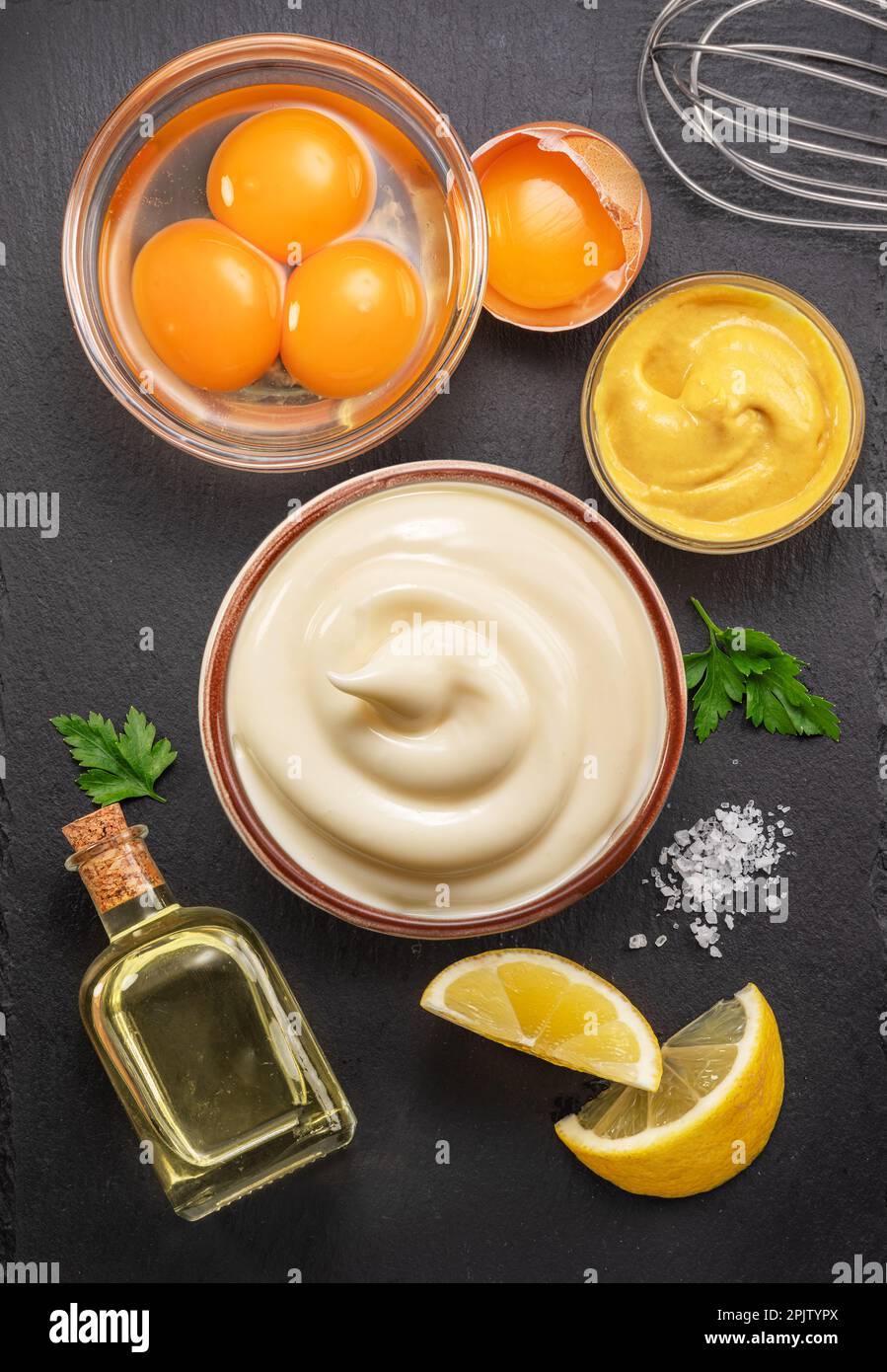 Hausgemachte Mayonnaise- und Mayonnaise-Zutaten auf schwarzem Steinschiefer-Servierteller. Flach verlegt. Stockfoto