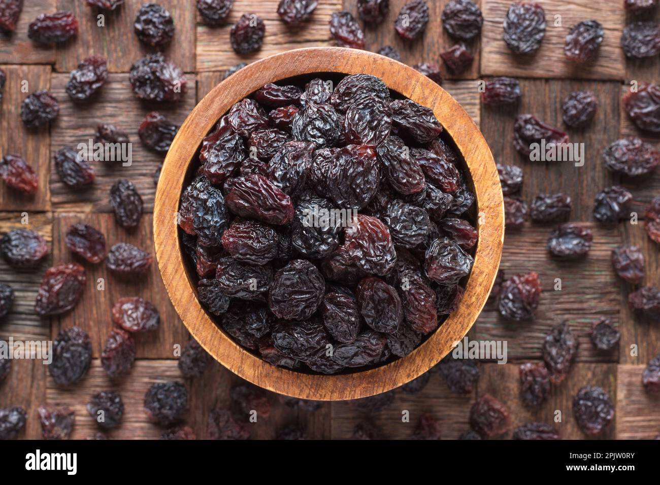 Getrocknete Weintrauben, dunkle Rosinen in der Schüssel auf Holztisch. Stockfoto