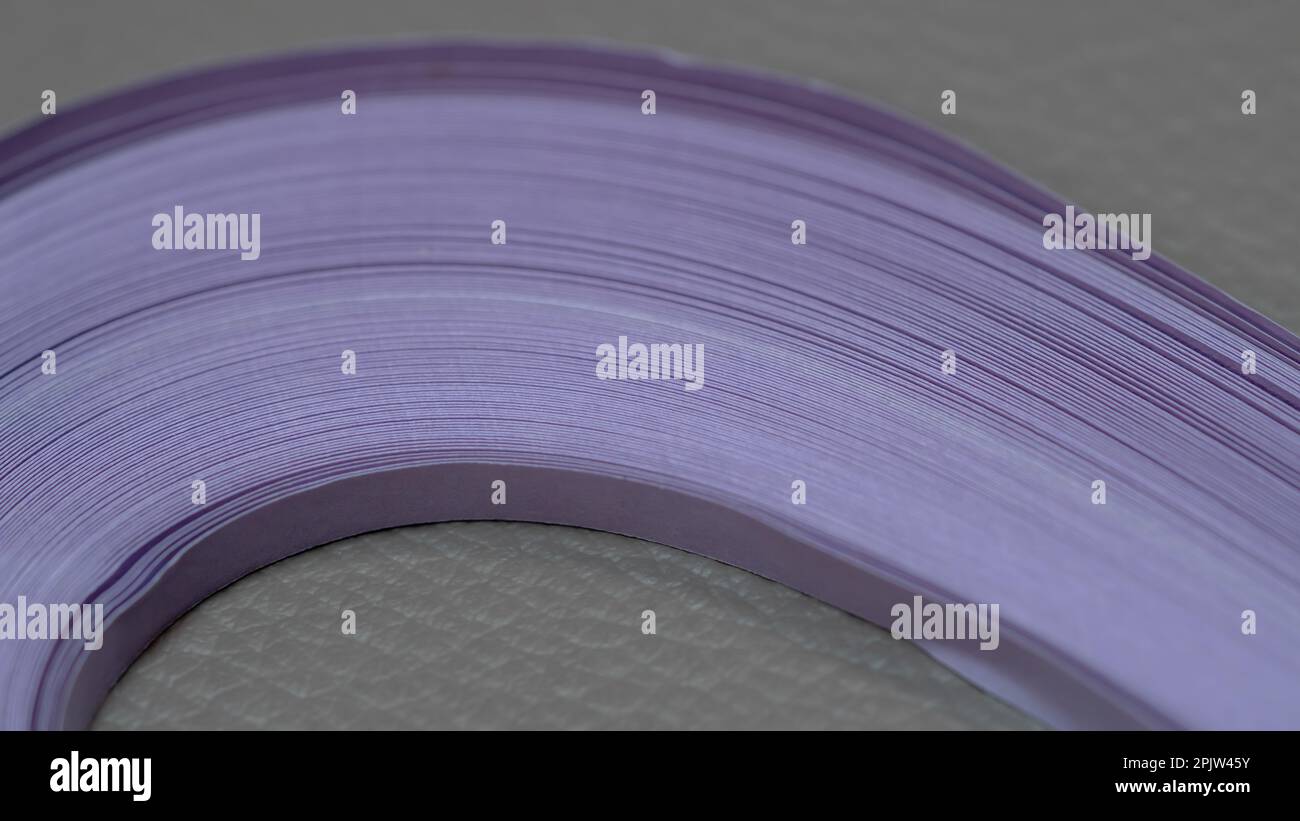 Nahaufnahme von lilafarbenen Papierstreifen auf grauem Hintergrund Makrofotografie Stockfoto