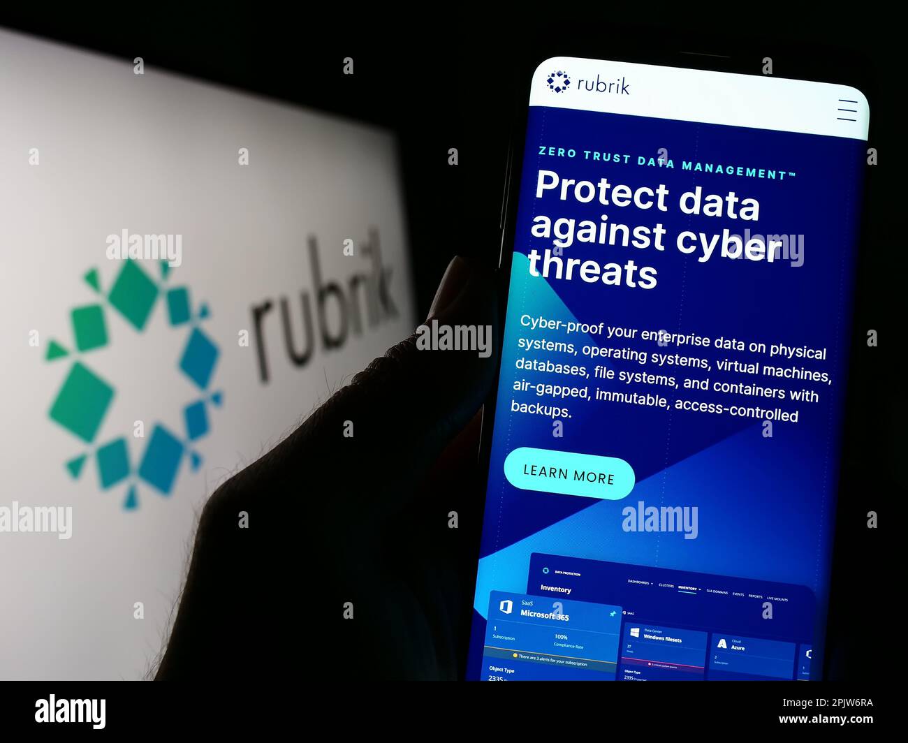 Person, die ein Mobiltelefon mit einer Webseite des US-Datenschutzunternehmens Rubrik Inc. Auf dem Bildschirm vor dem Logo hält. Konzentrieren Sie sich auf die Mitte des Telefondisplays. Stockfoto