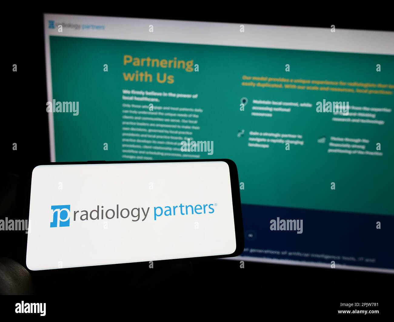 Person, die ein Mobiltelefon mit dem Logo des amerikanischen Gesundheitsunternehmens Radiology Partners Inc. Auf dem Bildschirm vor der Webseite hält. Konzentrieren Sie sich auf das Display des Telefons. Stockfoto