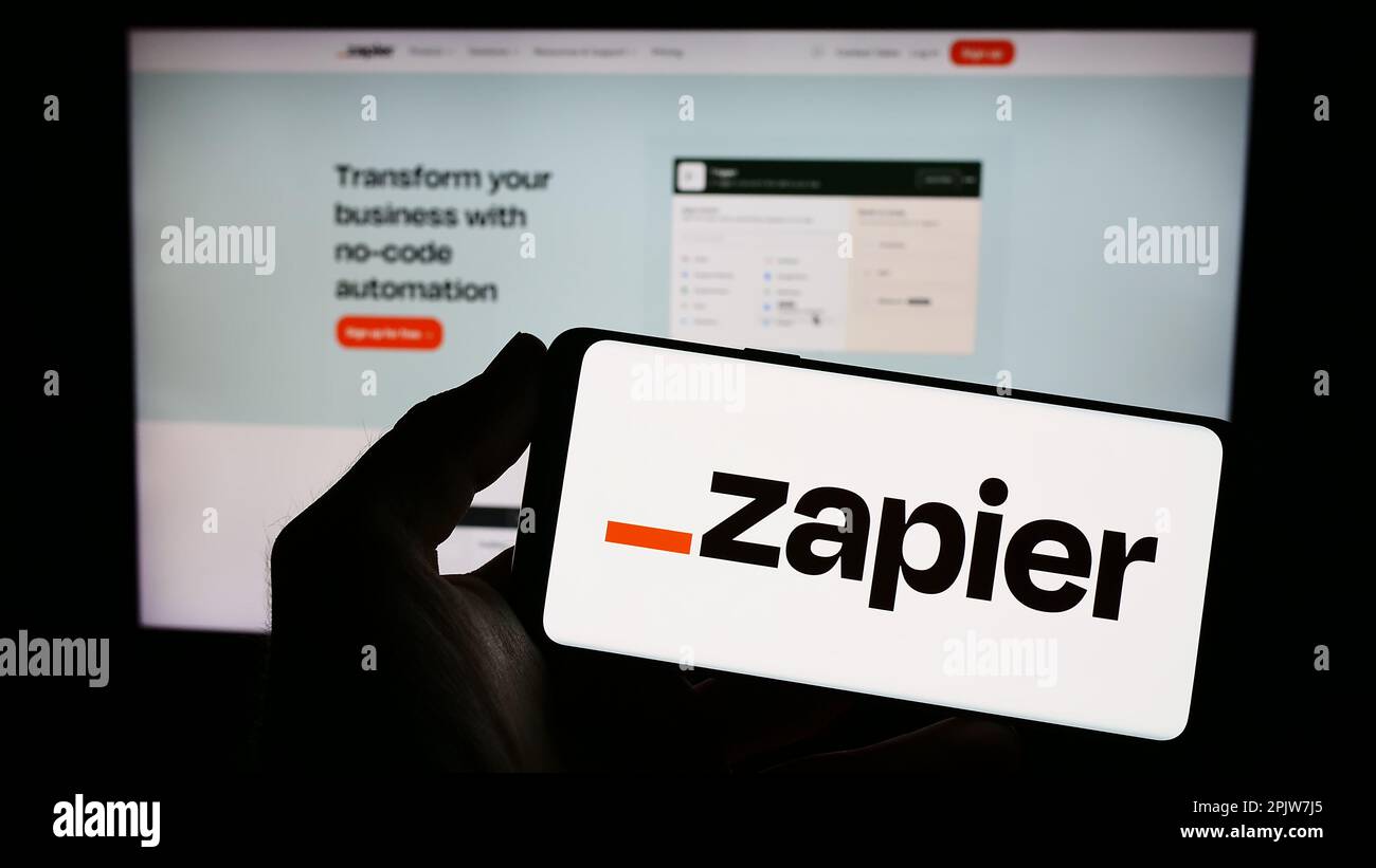 Person, die ein Smartphone mit dem Logo des US-amerikanischen Automationssoftwareunternehmens Zapier Inc. Auf dem Bildschirm vor der Website hält. Konzentrieren Sie sich auf das Display des Telefons. Stockfoto