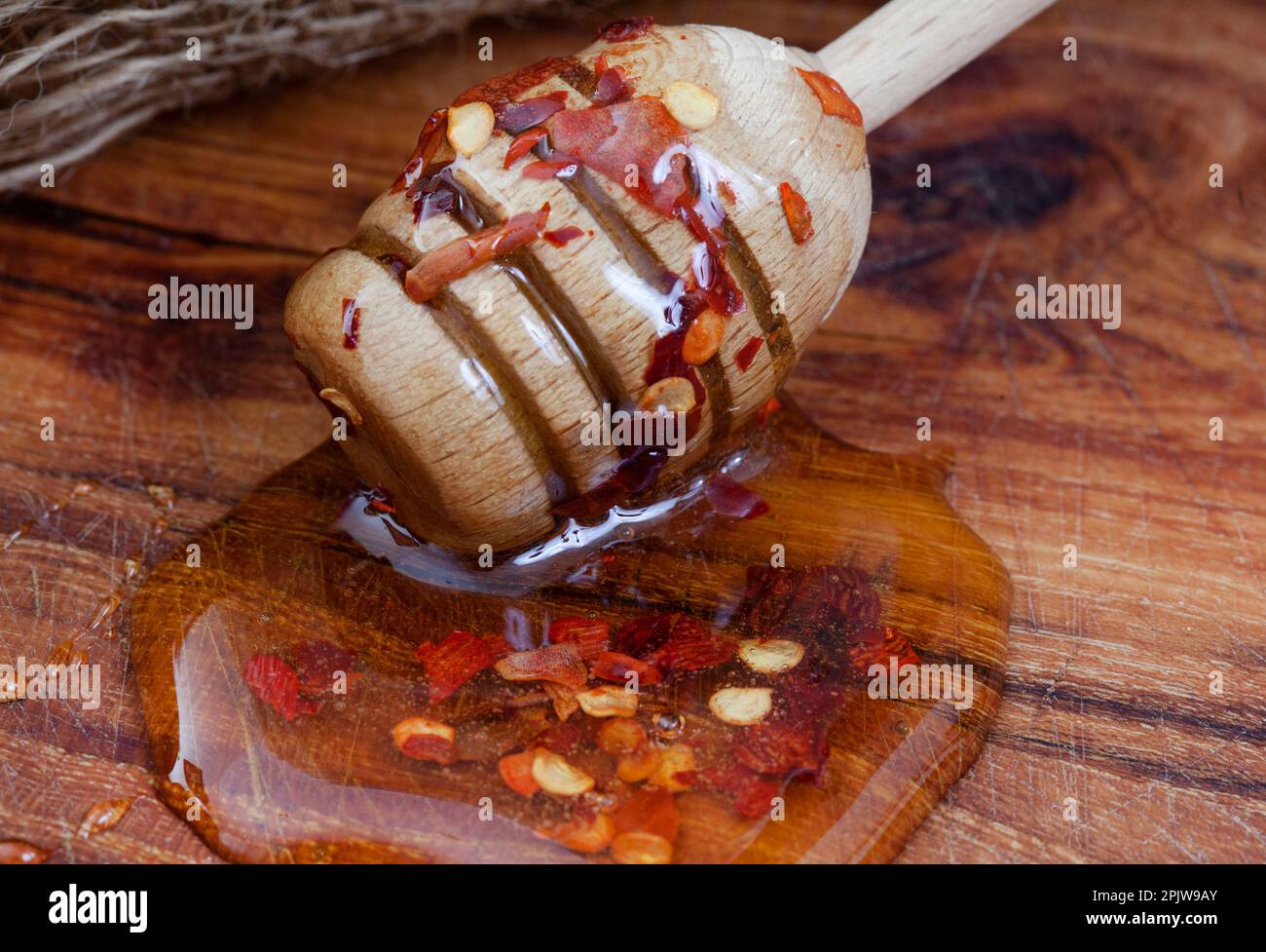 Heißer Honig oder Chilihonig mit Honigtropfer auf einem rustikalen Holztisch Stockfoto