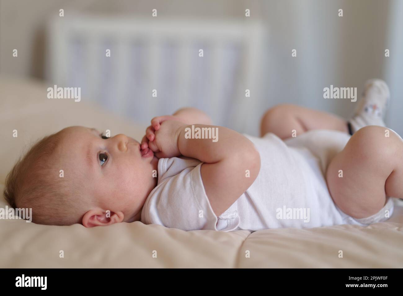 Ein 3 Monate alter Junge, der auf einem Bett liegt Stockfoto