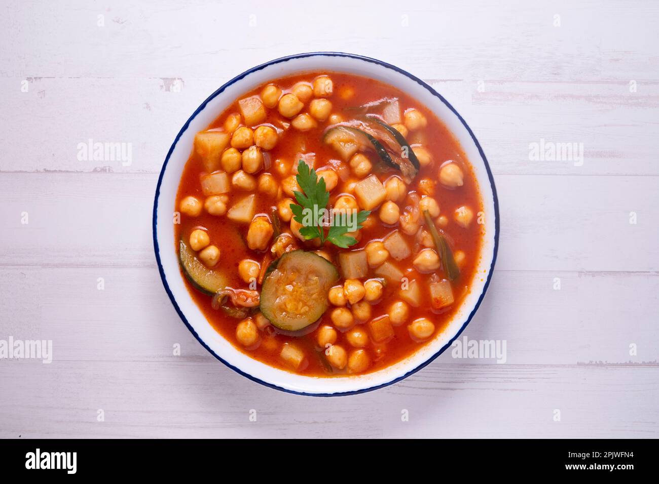 Typisch spanisches Gericht mit Kichererbseneintopf mit Gemüse wie Karotten, Paprika oder Zucchini. Stockfoto