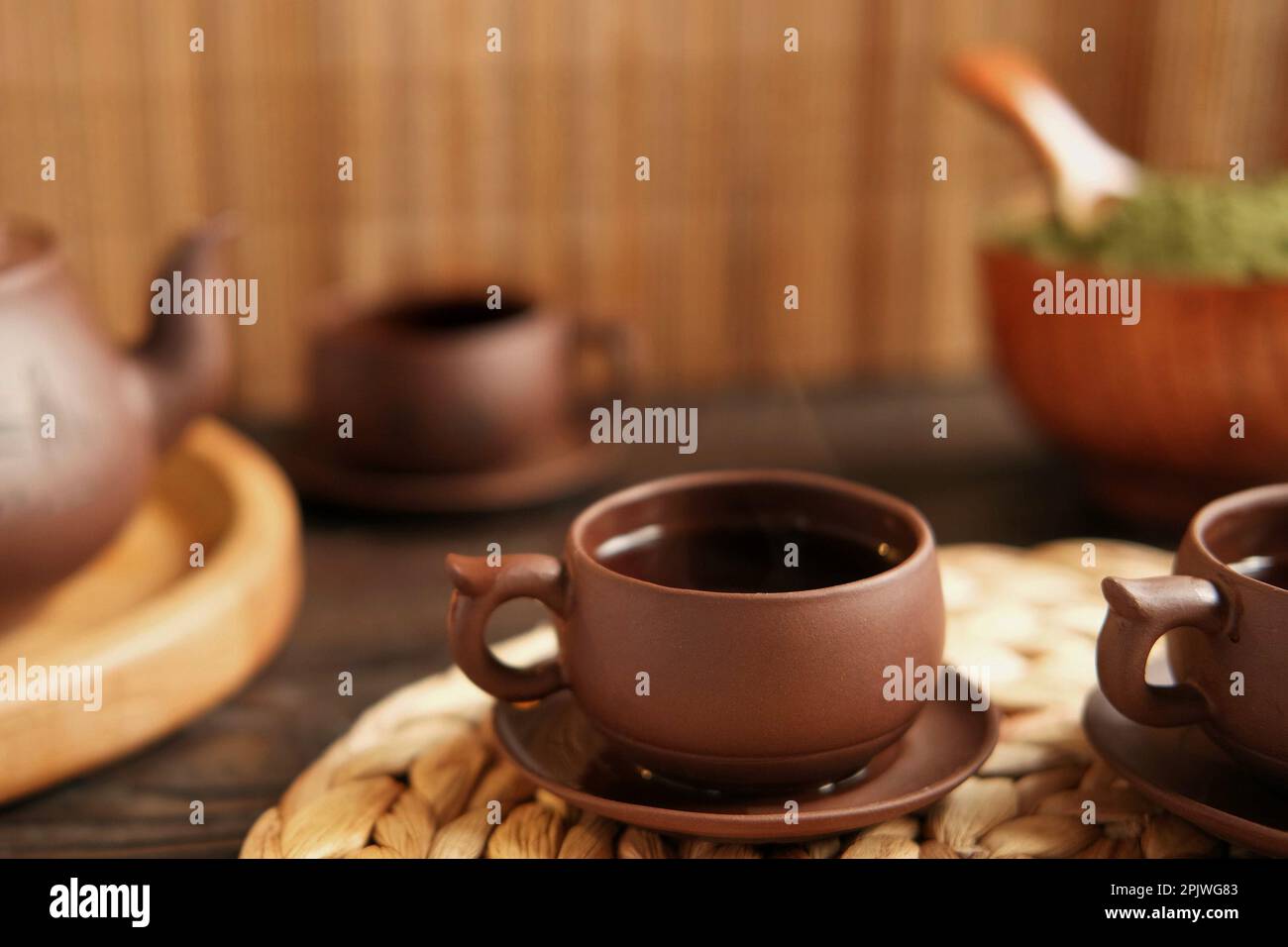 Teezeremonie. Traditionelles Asiatisches Teeutensil, Serviert Authentisches Set. Person, die Tee von der Teekanne aus brauner Keramik bis zur Teekanne einschenkt. Bambusschale. Lifestyle. Wir Stockfoto