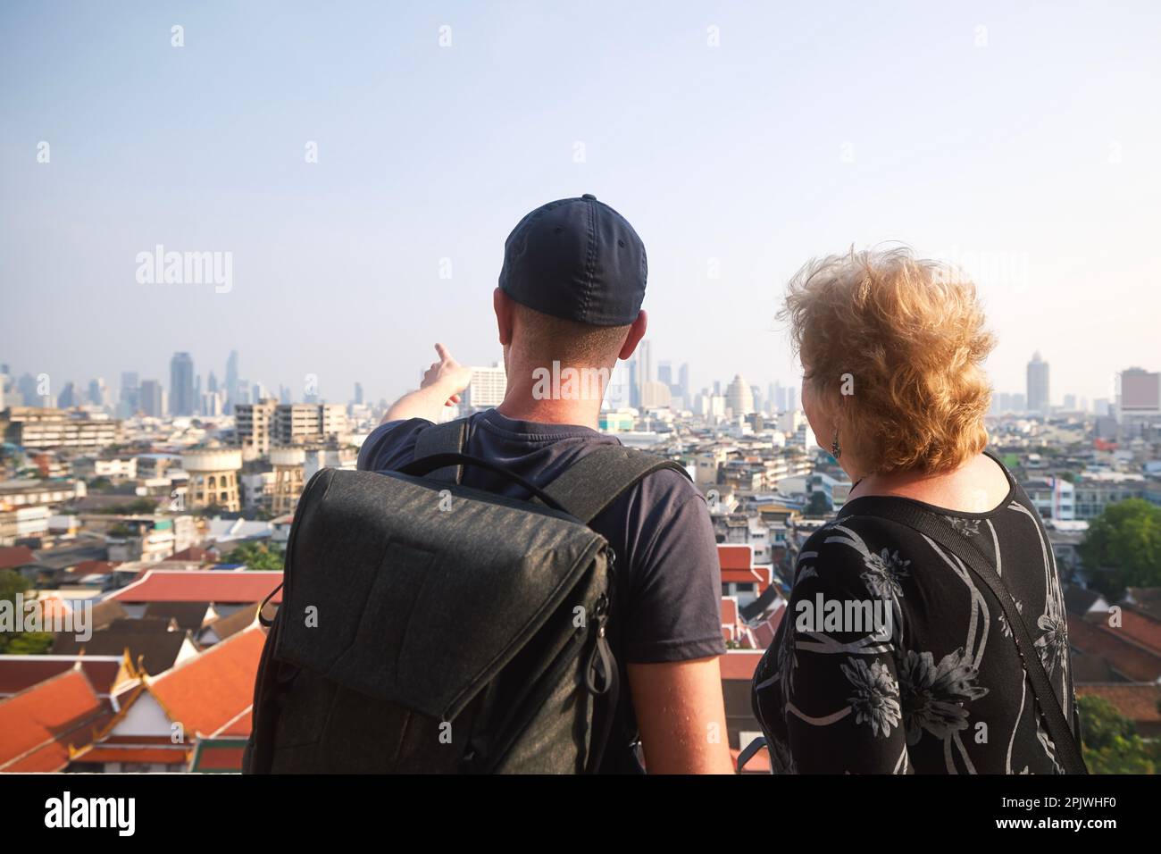 Zwei Touristen in Bangkok. Ein erwachsener Mann reist mit seiner leitenden Mutter und zeigt ihre urbane Skyline mit Wahrzeichen und Wolkenkratzern. Stockfoto