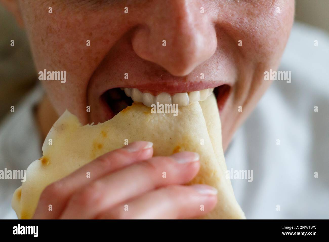Eine Sommersprossen-junge Frau, die einen Pfannkuchen isst Stockfoto