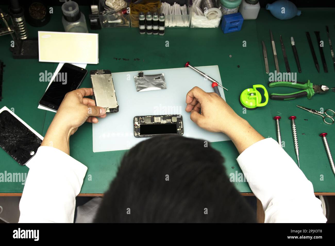 Beobachten eines Bedieners bei der Reparatur eines Smartphones in seiner kleinen Werkstatt Stockfoto