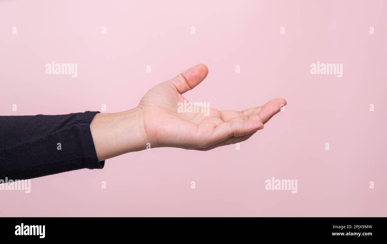 Nahaufnahme der Hand einer Frau, die bereit ist, zu helfen oder zu empfangen, isoliert auf pinkfarbenem Hintergrund. Helfende Hand zur Rettung ausgestreckt. Stockfoto