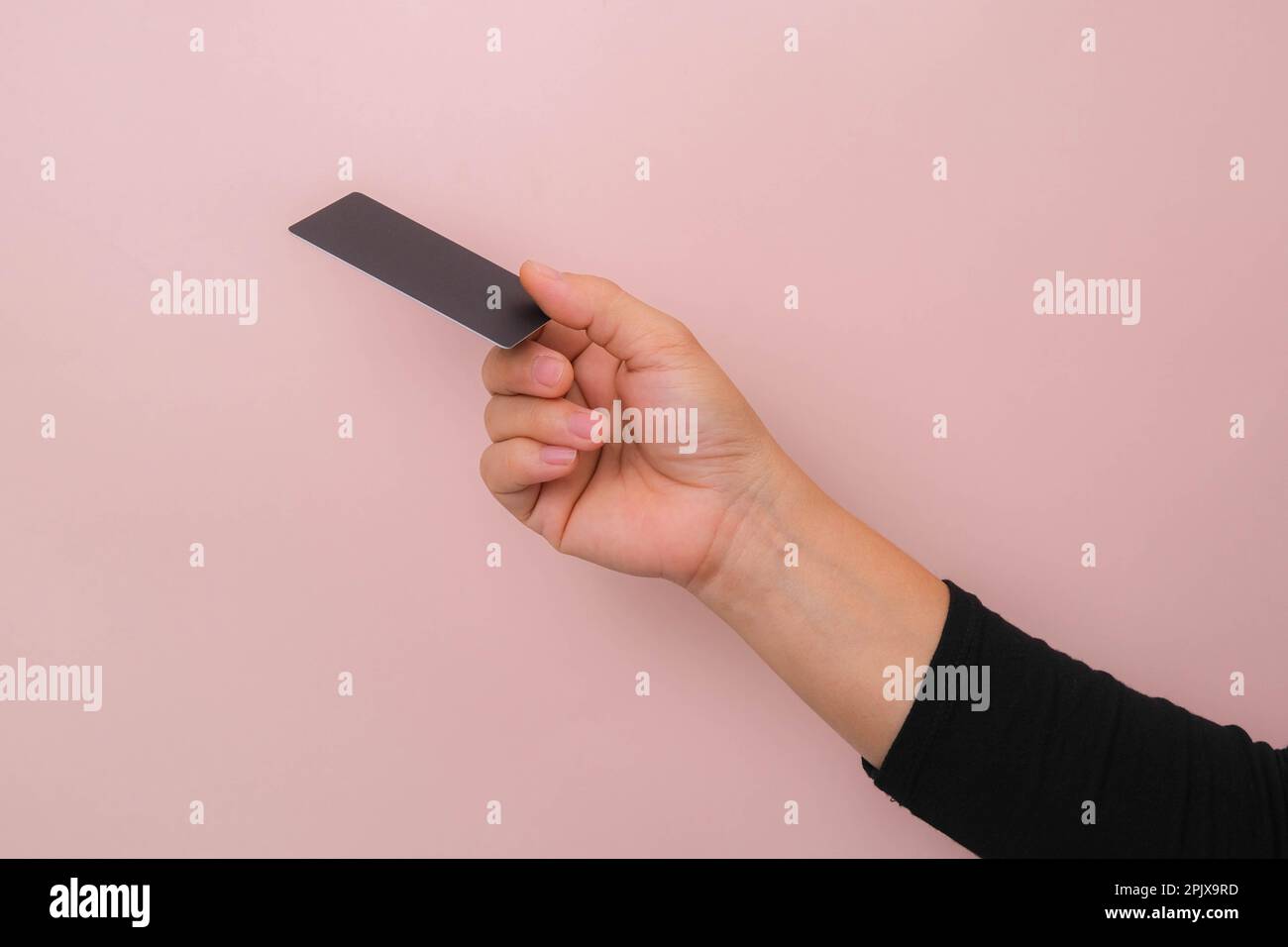 Nahaufnahme der Hand einer Frau mit schwarzer Karte isoliert auf pinkfarbenem Hintergrund. Stockfoto