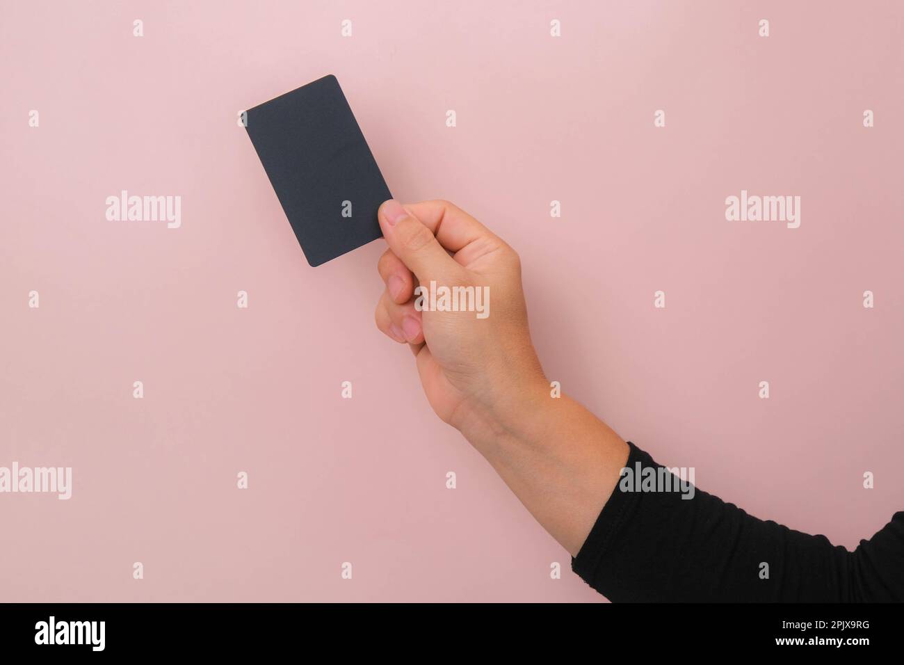 Nahaufnahme der Hand einer Frau mit schwarzer Karte isoliert auf pinkfarbenem Hintergrund. Stockfoto