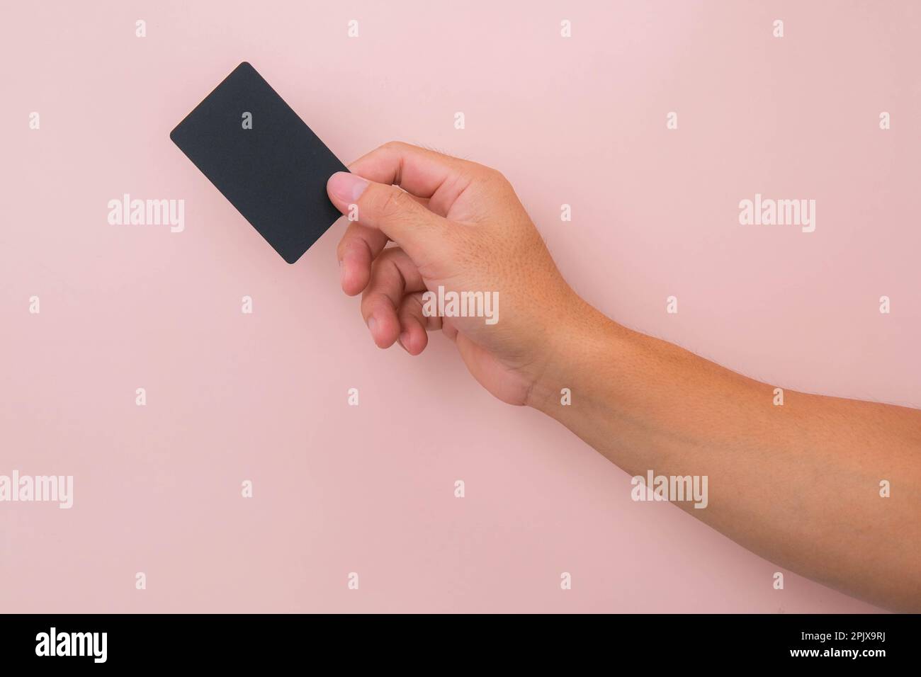 Nahaufnahme der Hand einer Frau mit schwarzer Karte isoliert auf pinkfarbenem Hintergrund. Stockfoto