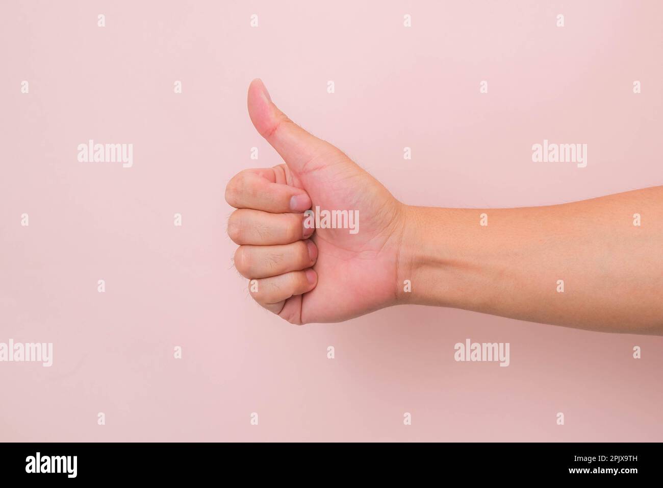 Nahaufnahme der männlichen Hand mit dem Symbol „Daumen nach oben“ auf pinkfarbenem Hintergrund. Stockfoto