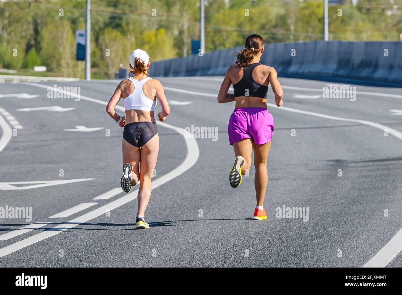 Zurück zwei Läuferinnen, die beim Overpass-Marathonrennen laufen, Ausdauersportwettbewerb, Joggingsportlerin Stockfoto