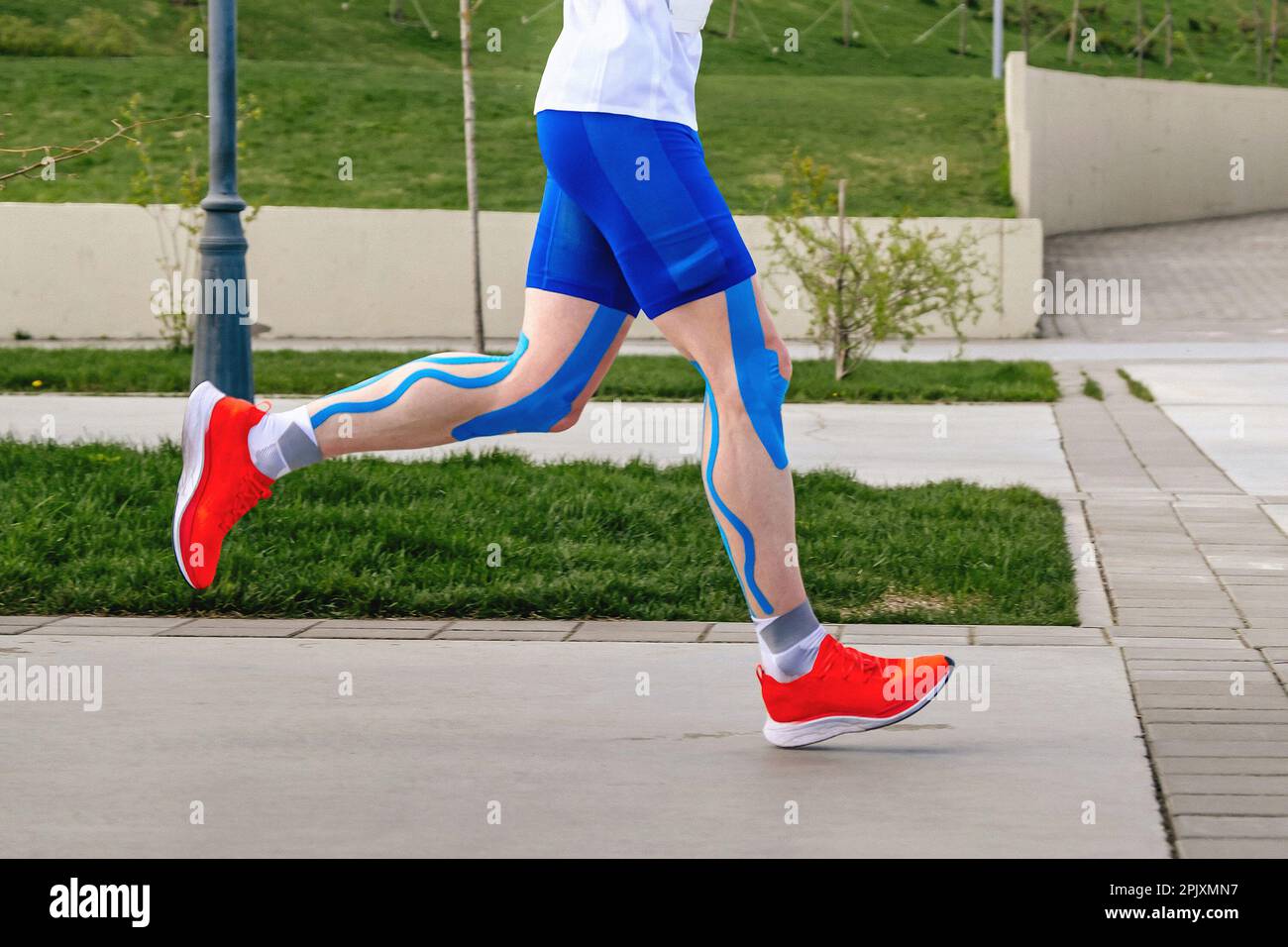Beine Läufer Athlet in blauer Kinesiotaping an Oberschenkeln, Wadenmuskeln und Knien, Marathon-Rennen Ausdauersport-Wettkampf Stockfoto