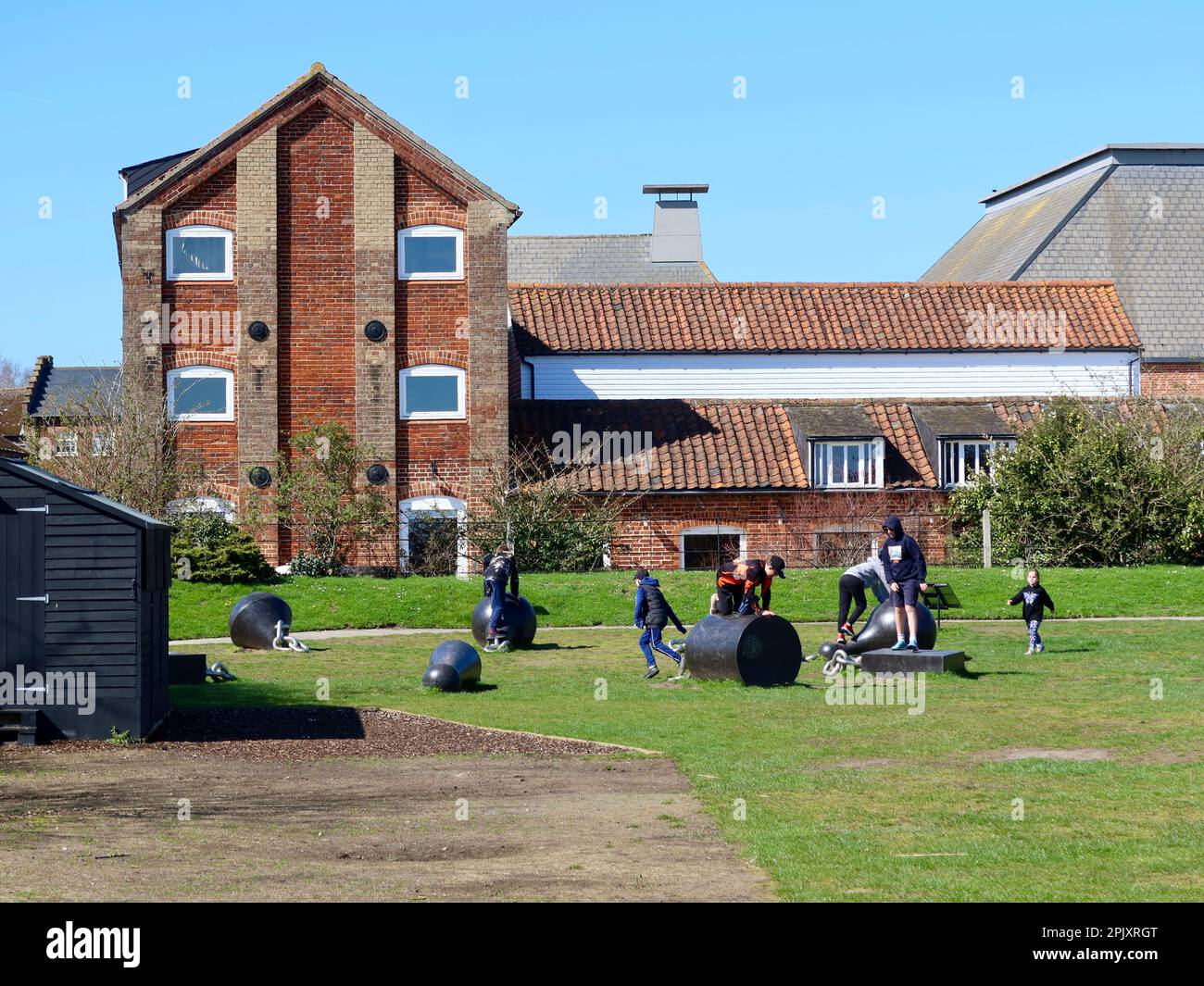 Snape Maltings, Suffolk, Vereinigtes Königreich - 4. April 2023 : ein sonniger Frühlingstag in dieser Touristenattraktion nahe der Küste. Kinder, die mit Kunstwerken spielen. Stockfoto