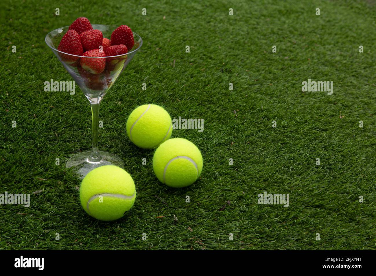 Erdbeeren und Tennisbälle auf Gras Stockfoto