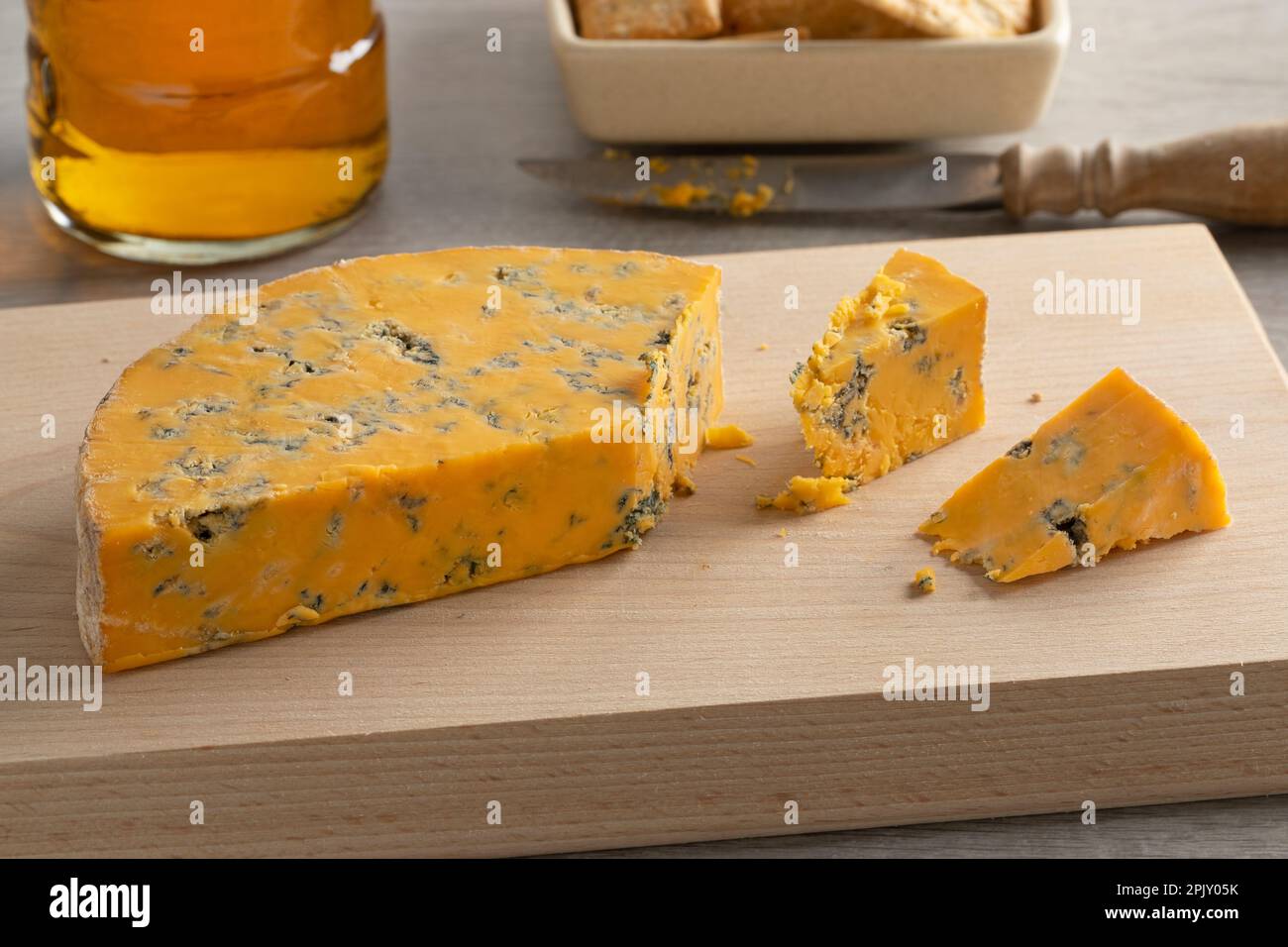 Ein Stück englischen Shropshire Blue Cheese auf einem Schneidebrett für einen Snack aus nächster Nähe Stockfoto