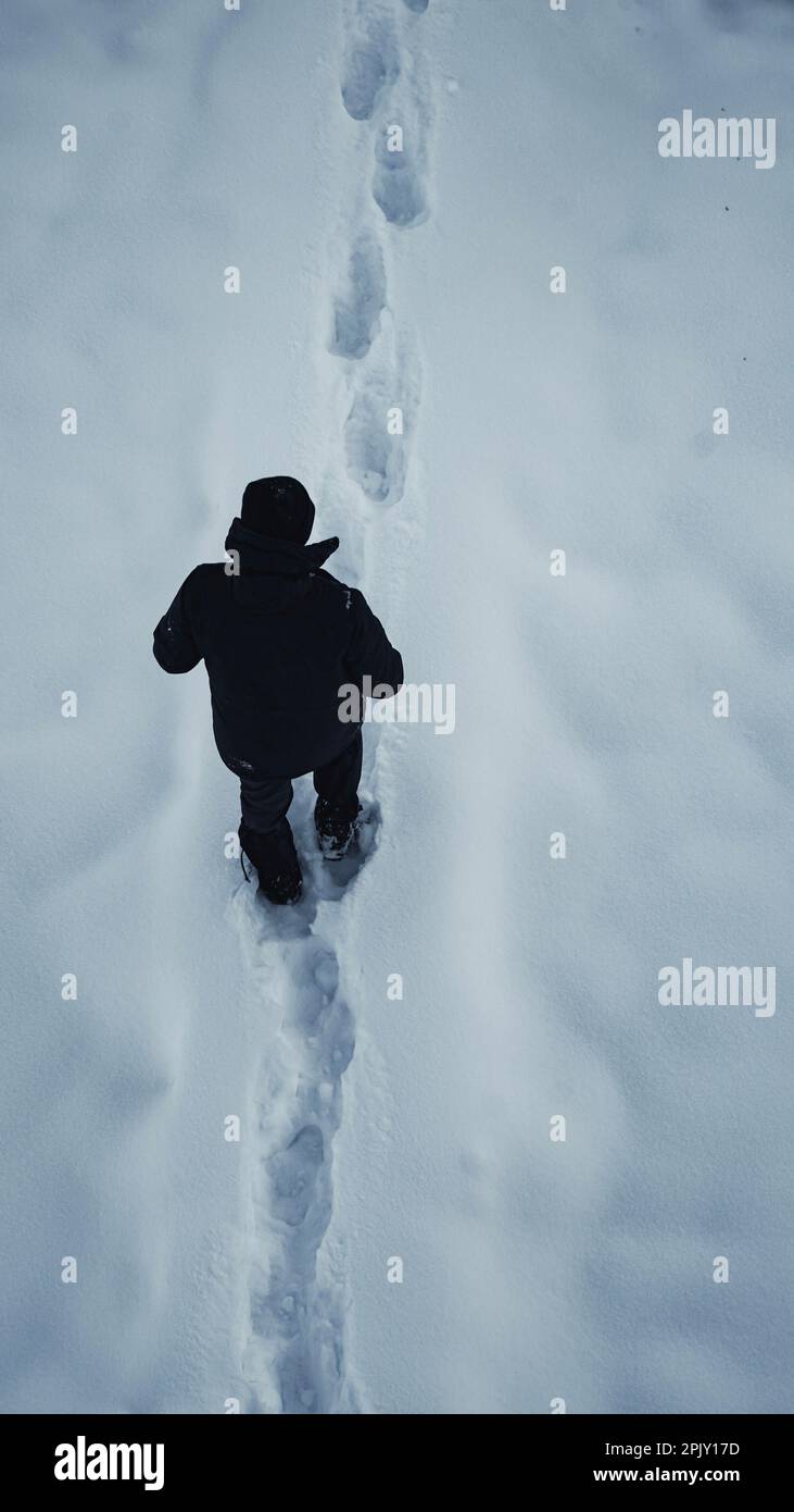 Ein Mann, der auf Schnee in der abgelegenen Natur Nordeuropas spaziert Stockfoto