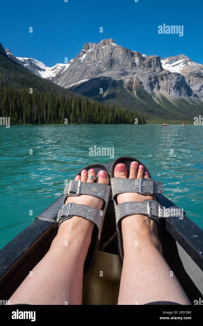 Damenfüße tragen glitzernde Sandalen auf einem Kanu. Aufgenommen am Emerald Lake im Yoho National Park Kanada Stockfoto