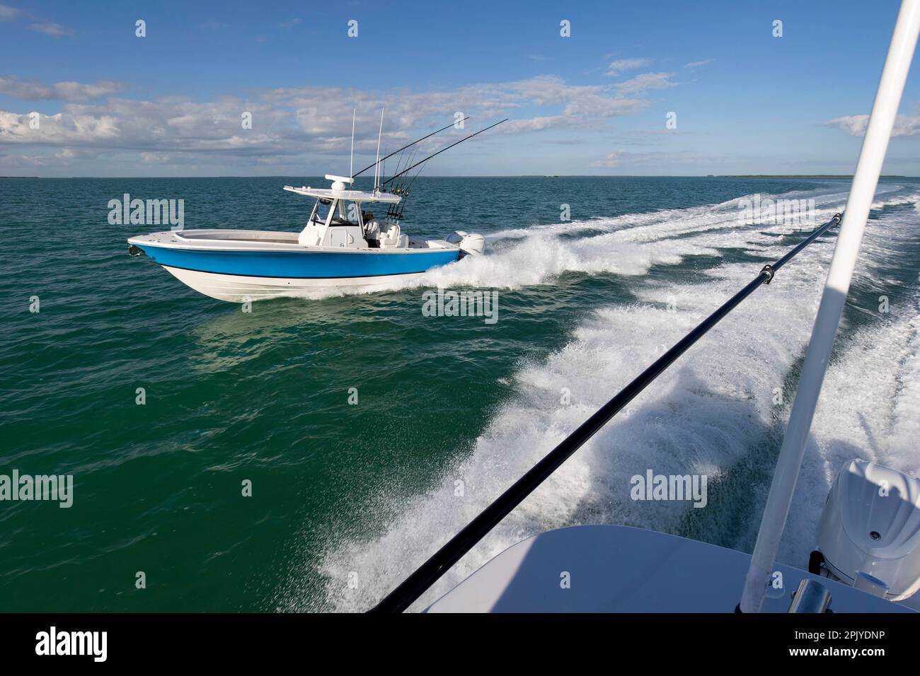 Blick auf das Heck eines rasenden Boots, während ein Fischerboot in der Mittelkonsole entlang fährt. Stockfoto
