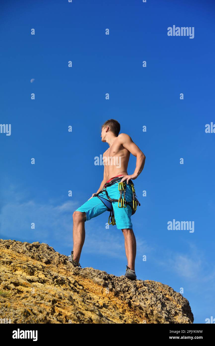 Ein Athletik-Kletterer, der auf dem Gipfel des Berges steht Stockfoto
