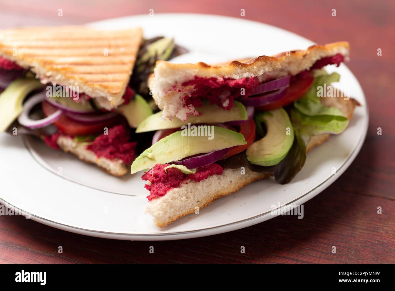 Gegrilltes Fladenbrot mit Rübenhummus, Tomaten und Avocados Stockfoto