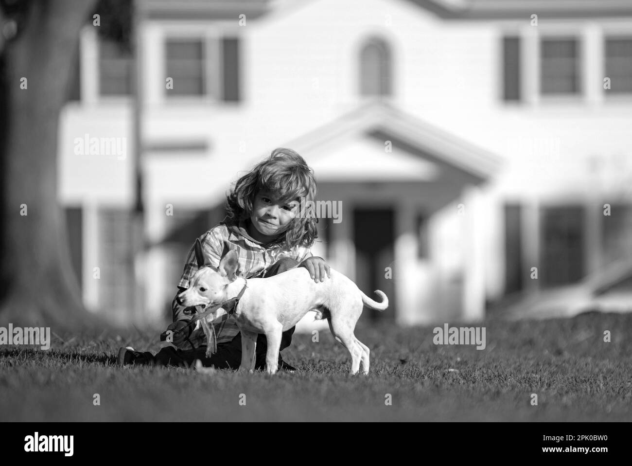 Kind umarmt liebevoll seinen Hund. Happy Little Kid Junge spielt mit Welpen im Garten. Stockfoto