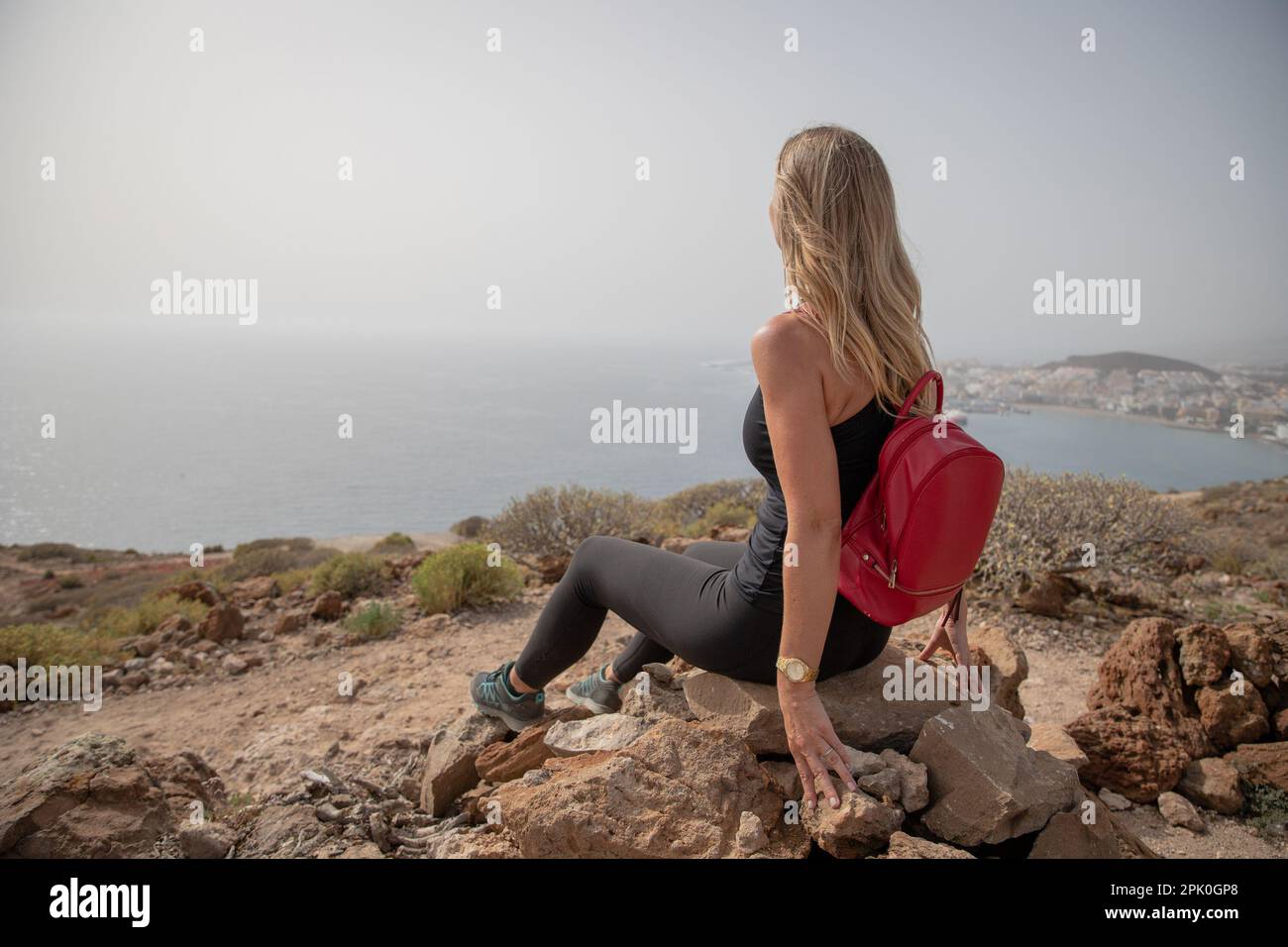 Ein Wanderer blickt auf das Meer, während er entspannt auf einem Felsen sitzt, die Liebe zur Natur und das Freiheitskonzept. Stockfoto