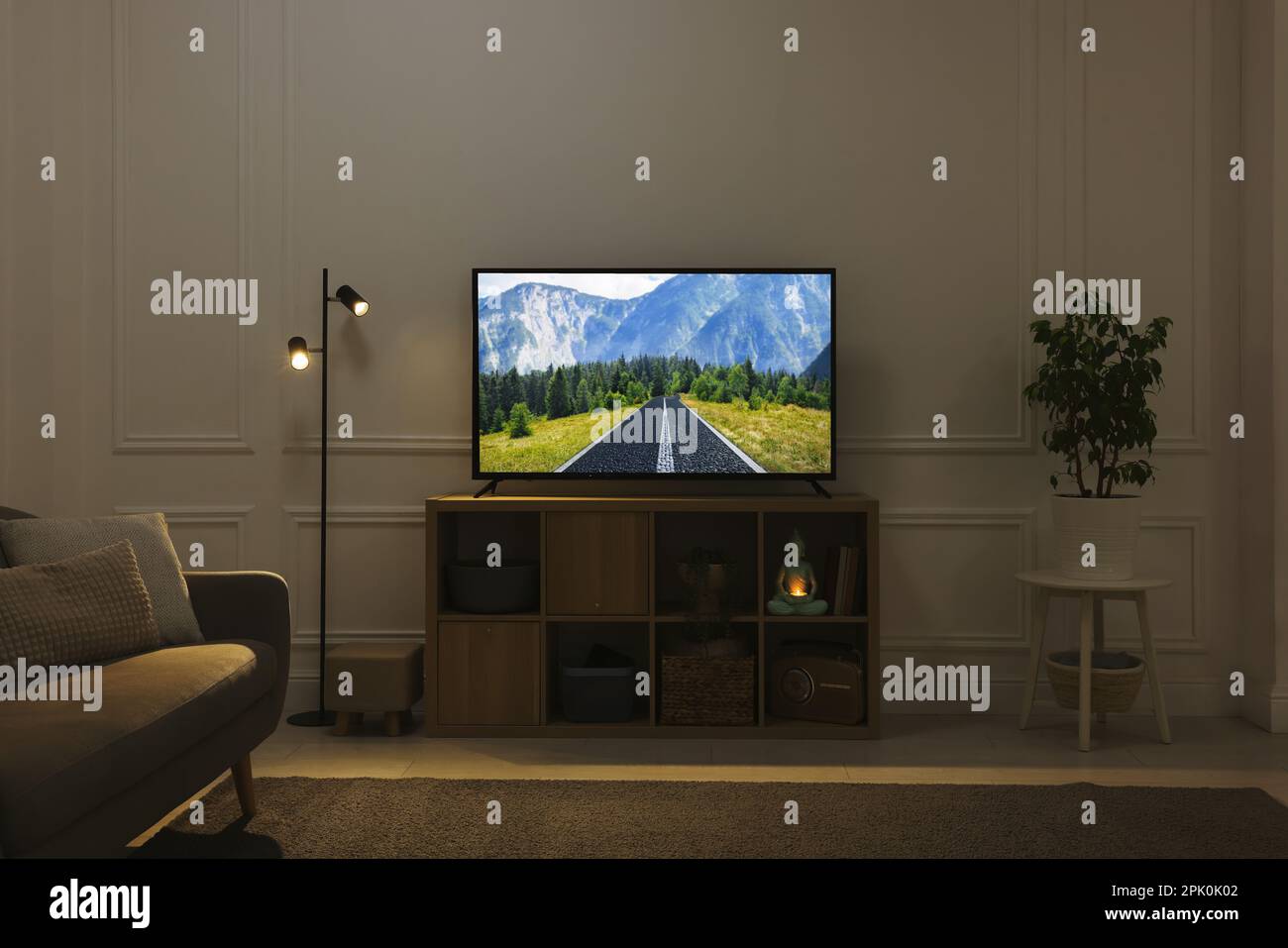 Moderner Fernseher auf Holzständer im Zimmer. Film mit Naturmotiv auf der Leinwand Stockfoto