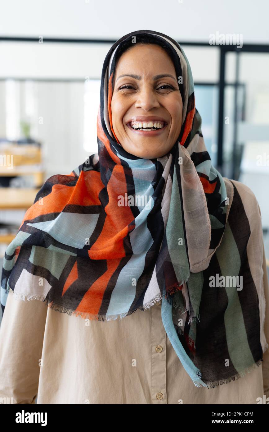 Porträt einer glücklichen muslimischen birassischen Geschäftsfrau im Kopftuch, die in einem modernen Büro in die Kamera schaut Stockfoto Porträt einer glücklichen muslimischen birassischen Geschäftsfrau im Kopftuch, die in einem modernen Büro in die Kamera schaut Stockfoto